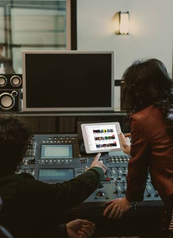 sound producers using tablet together at recording studio with youtube website on screen